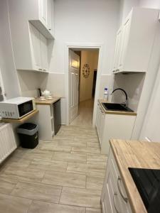 a kitchen with white cabinets and a tile floor at Apartament White in Olsztyn
