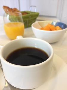 a cup of coffee and a bowl of fruit and a glass of orange juice at Hôtel De France - Restaurant L'insolite in Douarnenez