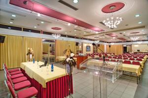 a conference room with tables and red chairs and a stage at Angelika Pallas Hotel in Igoumenitsa