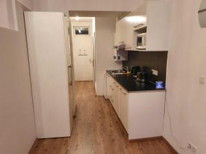cocina con armarios blancos y suelo de madera en Vibrant Red Apartment I contactless Check-In, en Viena