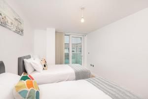 two beds in a white room with a window at Skyvillion - Station Road Apartment with Balcony & Parking in New Barnet