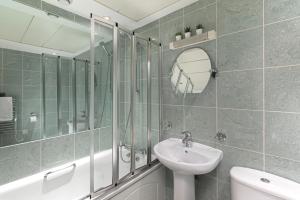 a bathroom with a sink and a mirror and a tub at Beautiful 2Bed 2Bath Apartment 4Mins to Train Station with WiFi and Free Parking in New Barnet +11 photos
