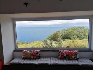 a large window with a bench in front of the ocean at Casa do Arcanjo in São Roque do Pico