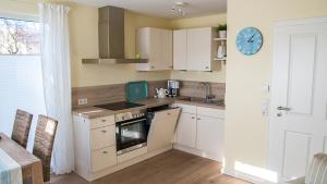 a kitchen with white cabinets and a clock on the wall at Beach Home in Böhl