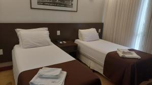 ブラジリアにあるHotel Bonaparte Blue Residence F 209のベッド2台とテーブルが備わるホテルルームです。