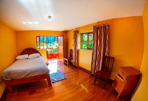 um quarto com paredes amarelas, uma cama e 2 janelas em Happy Land Valle Sagrado em Urubamba