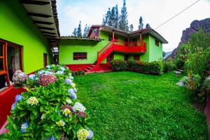 ein grünes und rotes Haus mit Blumen im Hof in der Unterkunft Happy Land Valle Sagrado in Urubamba