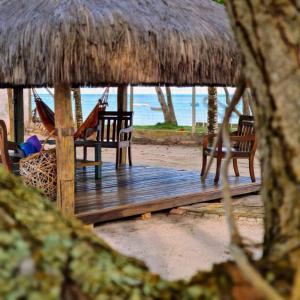 eine Holzterrasse mit Stühlen und einer Hängematte am Strand in der Unterkunft Pousada São Francisco in Cumuruxatiba