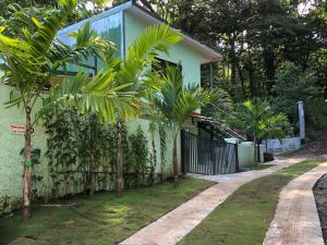 a house with palm trees next to a fence at Casa Encantada offers you Two-Bedroom House, 1 Tiny Apartment & 3 Double Rooms in Manuel Antonio