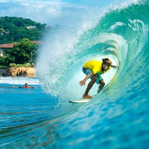 un hombre montando una ola en una tabla de surf en el océano en Nicawaves en Popoyo