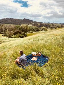 a person sitting on a blanket in a field at Aranui Farmstay in Waitomo Caves