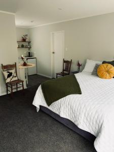 - une chambre avec un grand lit blanc et deux chaises dans l'établissement Aranui Farmstay, à Grottes de Waitomo