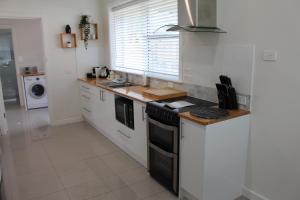 a kitchen with white cabinets and a stove top oven at Rosa's Apartment in Mount Gambier