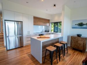 a kitchen with a refrigerator and a counter with stools at Bay Vista Beauty - Pōhara Holiday Home in Pohara
