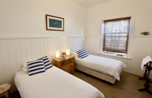 a bedroom with two beds and a window at The Snug in Robe