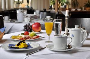 un tavolo con piatti di cibo e bicchieri di succo d'arancia di Dom Hotel a Augusta (Augsburg)