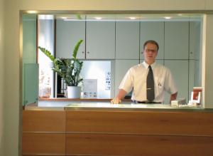 a man in a tie standing at a counter at Dom Hotel in Augsburg