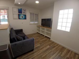 a living room with a couch and a flat screen tv at A Casa da Mila - Beach House in Costa da Caparica