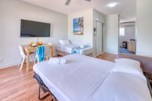 a room with a bed, table, chairs and a television at Noosa Sun Motel in Noosaville