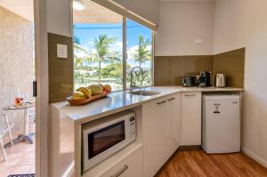 una cocina con fregadero y microondas en Noosa Sun - On the Noosa River, en Noosaville