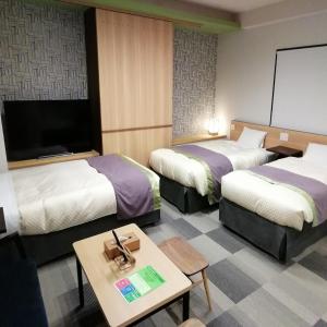 a hotel room with two beds and a table at Hotel Yururito Osaka in Osaka