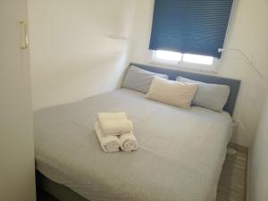 uma pequena cama com toalhas e uma janela em A Casa da Mila - Beach House em Costa da Caparica