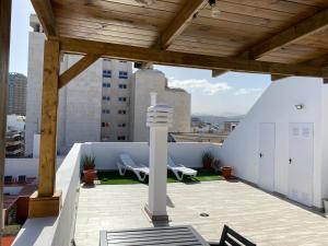 un patio con techo de madera y 2 sillas. en Holiday Home & Rooftop Lounge, en Las Palmas de Gran Canaria