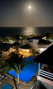 a view of a swimming pool at night with the ocean at Pousada Vale do Luar in Canoa Quebrada