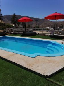 een groot blauw zwembad met twee parasols bij Hostal los Almendros de Canela in Canela Baja