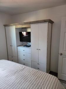 a bedroom with a bed and a tv and white cabinets at Greer Point Trails End Cabins in Greer