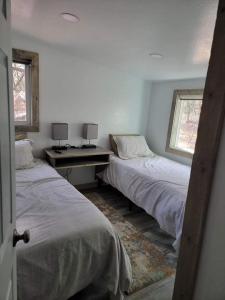 a bedroom with two beds and a desk and two windows at Greer Point Trails End Cabins in Greer