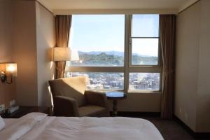 a hotel room with a bed and a chair and a window at Rhine Inn in Keelung