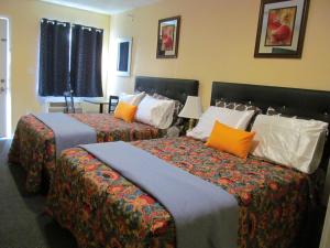 2 camas en una habitación de hotel con almohadas naranjas en Western Motel, en Lovell