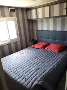 a bedroom with a bed with red pillows and a window at Mobilhome in Pornic