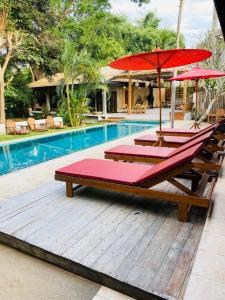 three lounge chairs with umbrellas next to a swimming pool at Veni Vana Valley Maetang in Ban Chang