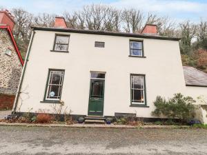 an old white house with a green door at Llysgwaun in Fishguard