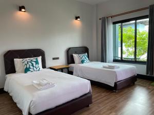 a hotel room with two beds and a window at Jeerat House จิรัสเฮ้าส์ in Phayao