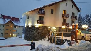 un bâtiment dans la neige avec une voiture garée devant dans l'établissement Pensiunea Piatra Graitoare, à Vartop