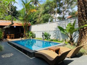una piscina in un cortile con sedie e tavolo di Kanda Villa ad Ubud