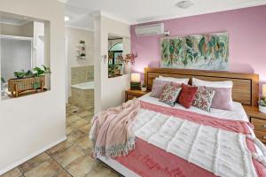 a bedroom with a large bed with pink walls at Villa Blue - Coastal Family Escape in Palm Cove