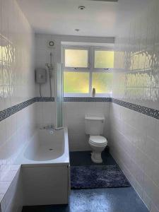 a bathroom with a tub and a toilet and a window at 3 bedroom bungalow set in private woodlands. in Upminster