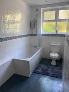 a bathroom with a tub and a toilet and a window at 3 bedroom bungalow set in private woodlands. in Upminster