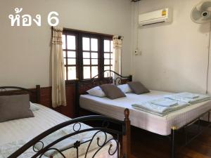 1 dormitorio con 2 camas y ventana en Pimpa House, en Ban Hua Nam Mae Sakut