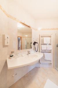 uma casa de banho branca com um lavatório e um espelho em Berglandhotel Untertheimerhof em Villandro