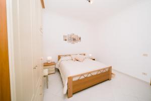 a white bedroom with a bed and a night stand at Rosemary Holiday House in Conca dei Marini