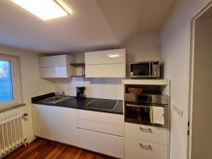 eine kleine Küche mit weißen Schränken und einer Mikrowelle in der Unterkunft Appartment Himmelblau in Friedrichshafen