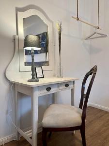 a desk with a lamp and a mirror and a chair at COSY PANKOW HOMES - Studios mit TV Stick in Berlin