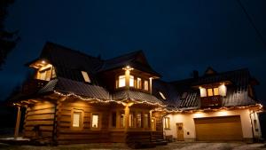 een groot houten huis met 's nachts verlichting bij Willa Hreśka in Bańska Niżna