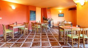 a restaurant with orange walls and tables and chairs at Penzion Dana in Benecko