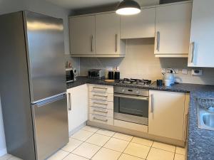 eine Küche mit weißen Schränken und einem Kühlschrank aus Edelstahl in der Unterkunft Marston House in Marston Green